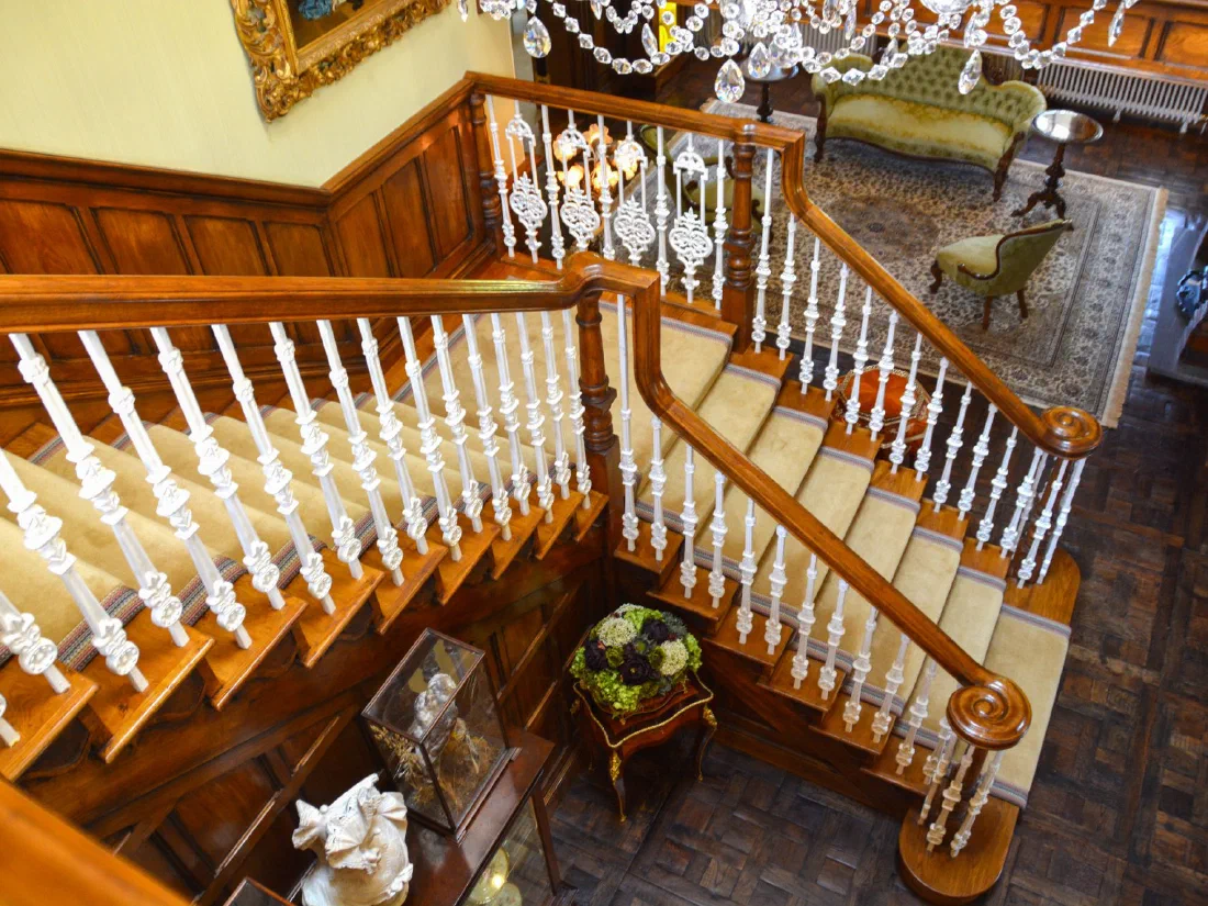 Oak staircase with cast-iron balusters and scrolled handrails, seen from the landing